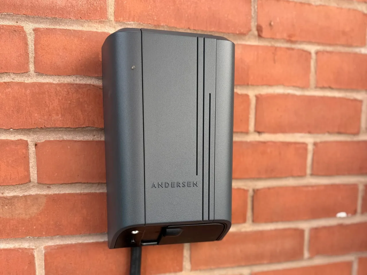 Grey Andersen Quartz EV charger mounted on a red brick wall