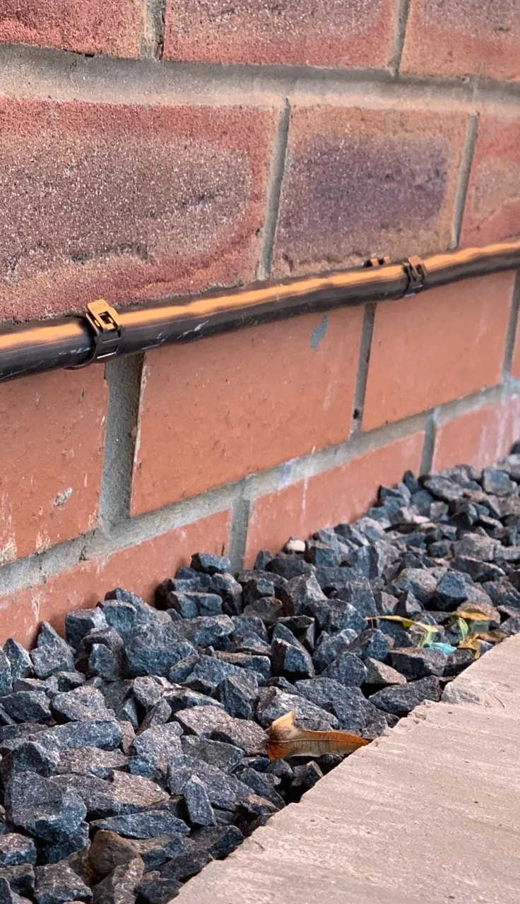 Close-up of D-Line clips holding an EV charger cable neatly along a brick wall above slate chippings