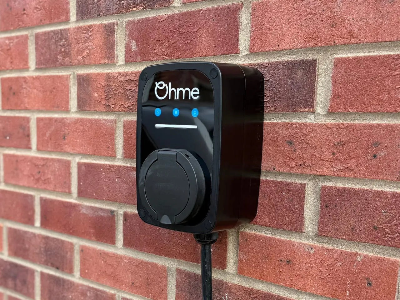 Black Ohme ePod EV charger mounted on a red brick wall