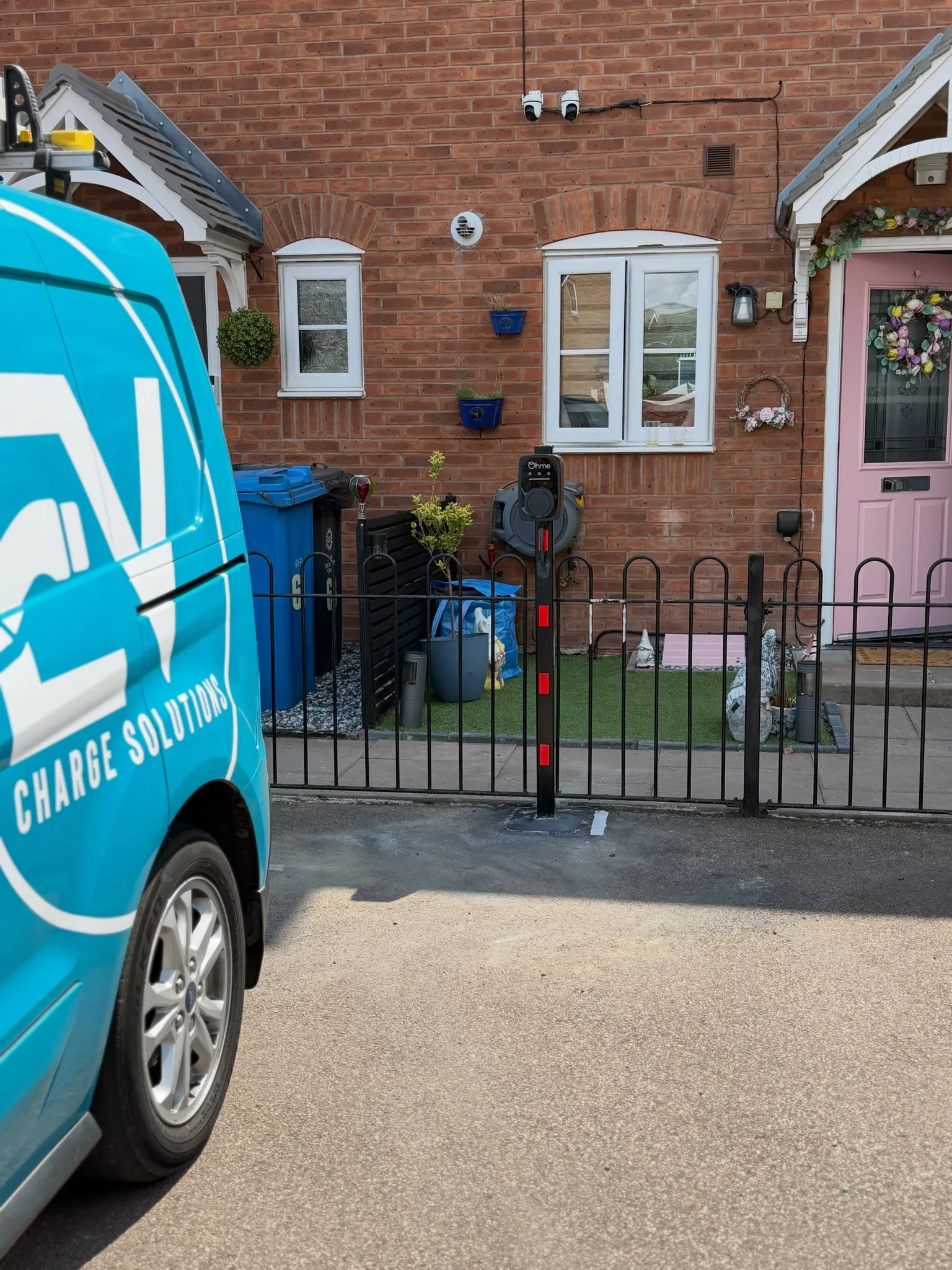 EV Charge Solutions van parked outside a brick house with a post-mounted Ohme EV charger behind the front railings